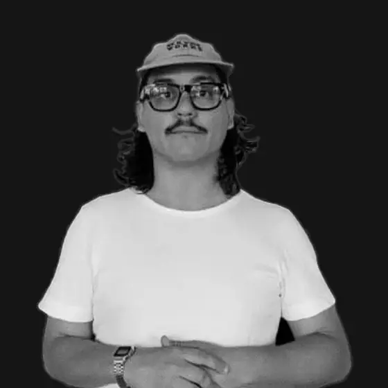 Nicolás Bronzina in a cap and glasses, hands clasped